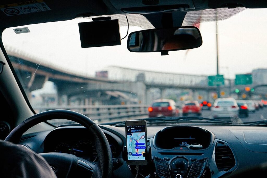 Conducteur vu de l'arrière au volant, smartphone de navigation fixé au tableau de bord, dans les bouchons