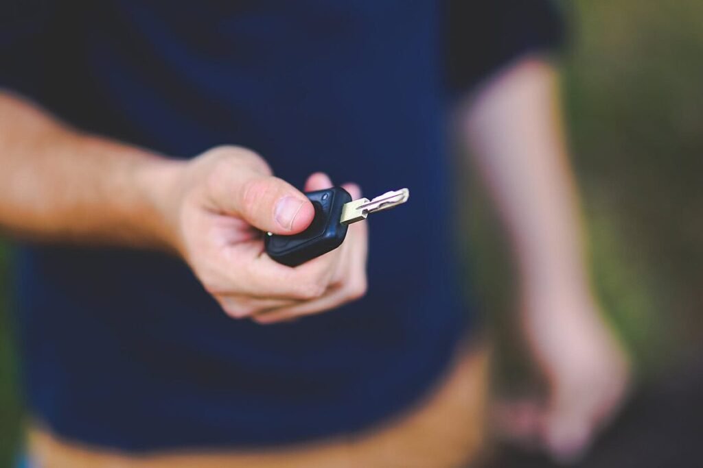 Hand die een autosleutel overhandigt aan iemand anders