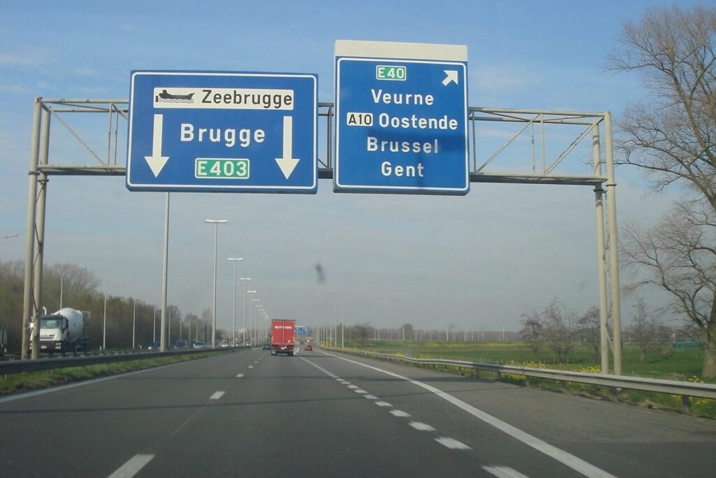 Blauwe wegwijzers boven de autosnelweg richting Brugge, Zeebrugge, Veurne, Oostende, Brussel en Gent