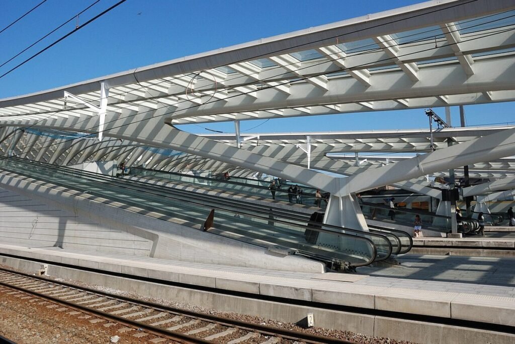 Bijna leeg perron van station Luik-Guillemins onder de witte overkapping, vrije sporen